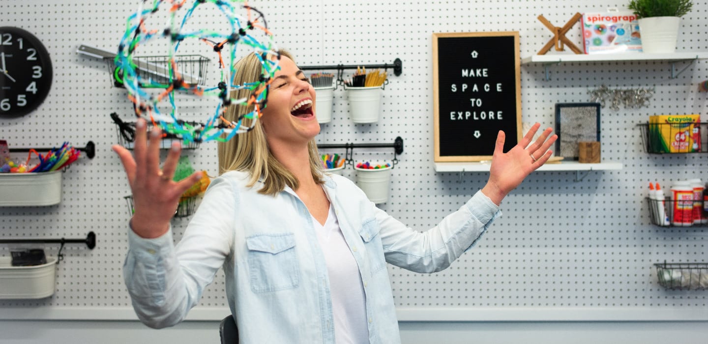 Mujer riendo jugando con una esfera de Hoberman en un espacio del fabricante.